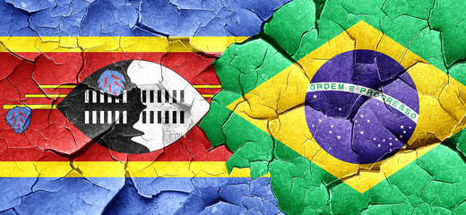 Swaziland flag with Brazil flag on a grunge cracked wall