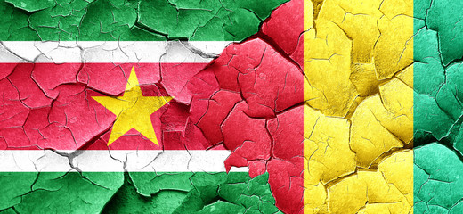 Suriname flag with Guinea flag on a grunge cracked wall