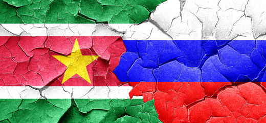 Suriname flag with Russia flag on a grunge cracked wall