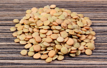 Heap of green lentil on wooden background