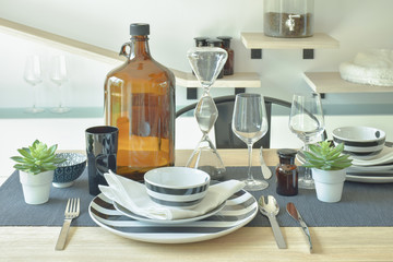 Fototapeta na wymiar Striped chinaware, wine glass and bottle setting on wooden dining table