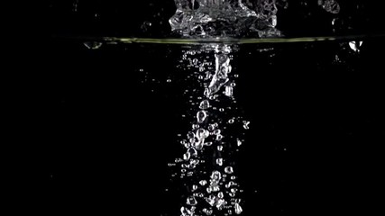 Two green apples fall down in water against black background, super slow motion - Powered by Adobe