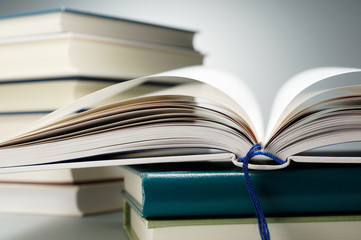 Stack of books and open book on gray background.
Close up of books and open book pages.
