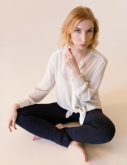 Beautiful woman in black leggings on beige background.