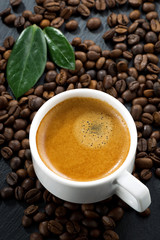 Naklejka premium cup of fresh espresso on coffee beans background, top view