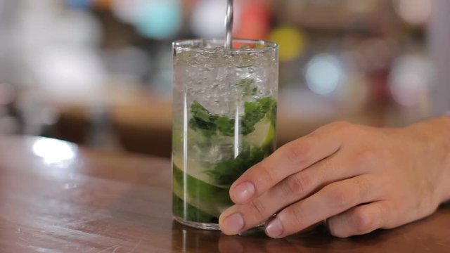 Bartender mixes mojito on wooden bar counter