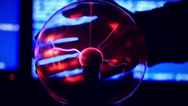 Plasma Ball - a transparent sphere filled with rarefied inert gas. Slowmotion of Hand touch the plasma ball against a blue background broken computer