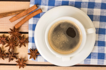 cup of coffee on a napkin and notepad with pen on wooden background