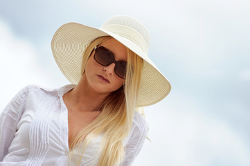 Junge blonde Frau mit Sonnenbrille und Hut