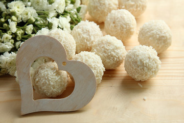 decorative heart with candy and flowers on white wooden background