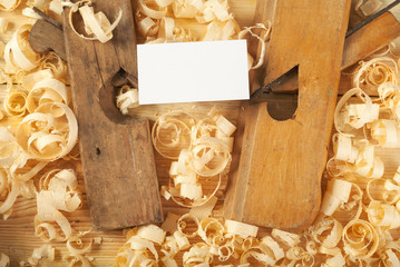 Business card on wooden table for carpenter tools with sawdust.