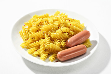 Expertly cooked fusilli with spice served with an accompanying sausages on white ceramic plate. Close up, high resolution product.