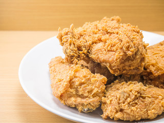 fried chicken on a white plate set on a wood table background