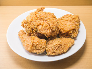 fried chicken on a white plate set on a wood table background