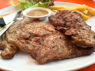 Close up steak pork with black pepper sauce, french fries and salad