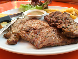Close up steak pork with black pepper sauce, french fries and salad