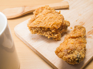 fried chicken on a chopping broad with a glass set on a wood background
