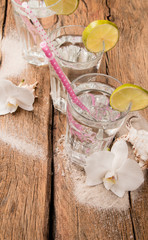 Cold water drink with ice and a slice of lime on wooden background