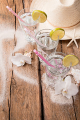 Cold water drink with ice and a slice of lime on wooden background