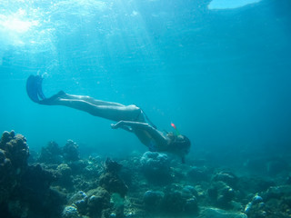 Underwater shot of the woman moving on the breath hold in the depth. Amed village, Bali, Indonesia
