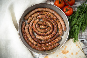 fried sausages on a frying pan on a wooden background. selective