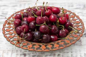 red cherries in a beautiful plate. light background