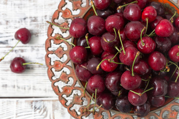 red cherries in a beautiful plate. light background
