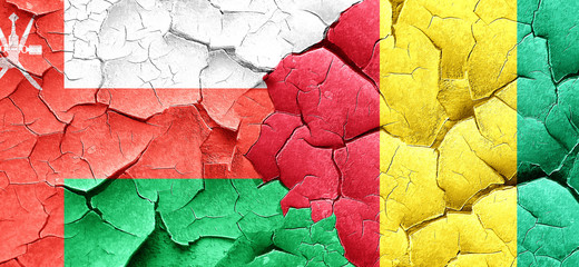 Oman flag with Guinea flag on a grunge cracked wall