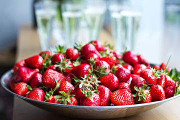 .Dish with strawberries and champagne glasses on the table. Dinner, party, bachelorette party, summer party, celebration.