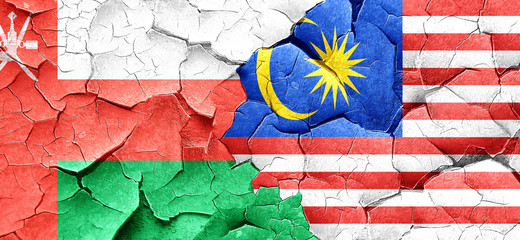 Oman flag with Malaysia flag on a grunge cracked wall