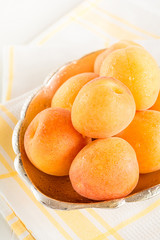 Eine Schale mit frischen Aprikosen steht auf einem Tisch.