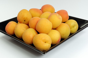 Ripe apricots on a black plate