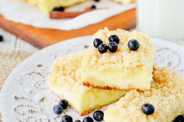 
rustic grated cheese cake with berries , with blueberries and milk on a wooden background