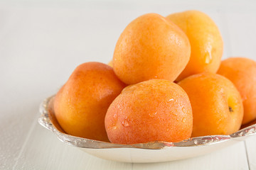 Eine Schale mit frischen Aprikosen steht auf einem Tisch.