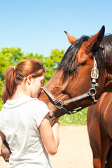 Obraz premium Young redhead teenage girl kissing her favorite chestnut horse.