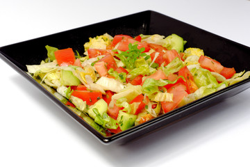 Vegetable salad on a black plate isolated