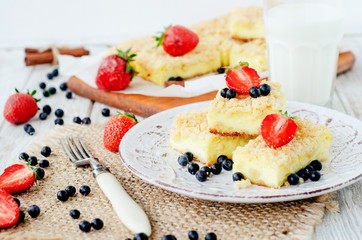 
rustic grated cheese cake with berries , with strawberries , blueberries and milk on a wooden background