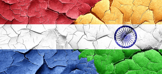 Netherlands flag with India flag on a grunge cracked wall