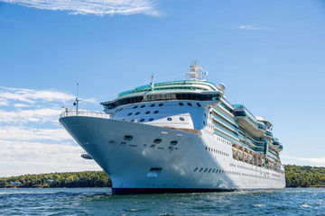 Fototapeta na wymiar Massive Cruise Ship on Blue water by Green Island