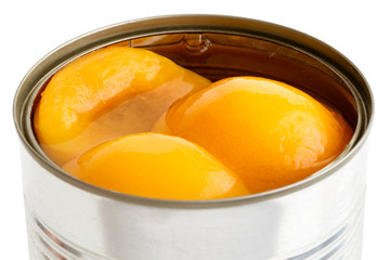 Detail of open can of peach halves in syrup on white background.