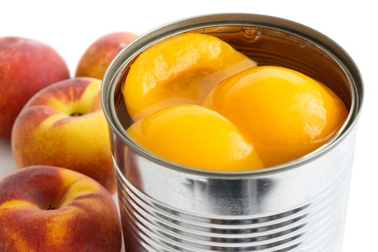 Fototapeta Detail of open can of peach halves in syrup on white background