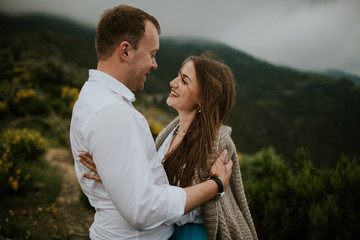 Fototapeta premium Young cute couple honeymoon walks holding their hands on dating in a beautiful place italy near ocean and mountains, hug, smile and talk to each other 