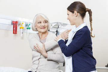 Physiotherapist Helping Smiling Senior Patient With Hand Exercis
