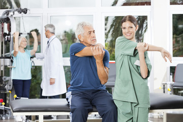 Obraz premium Nurse Guiding Senior Man In Stretching Exercise