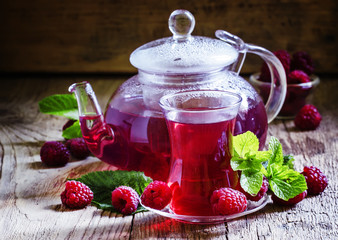 Summer raspberry tea with mint in a glass, vintage wooden backgr
