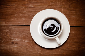 White cup of coffee on old wooden table. Toned