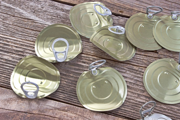 Tin can lids with opener on wooden background