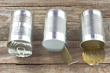 Three open empty tin can on wooden background
