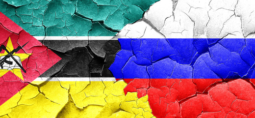 Mozambique flag with Russia flag on a grunge cracked wall