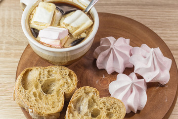 Chewing marshmallows, meringue and coffee cup on a wooden board